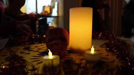 People sitting at a Halloween-themed table eating spooky snacks, with a decorative skull and burning candles creating a dark festive atmosphere. Warm candlelight and horror-style decorations captured - Powered by Adobe