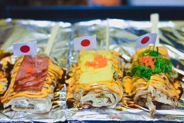 Japanese-style crepes with toppings, sauce, and small flags.
