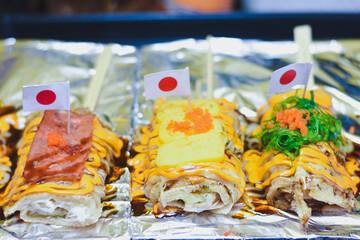 Japanese-style crepes with toppings, sauce, and small flags.