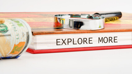A close-up view showcases a book titled Explore More alongside a magnifying glass and rolled...