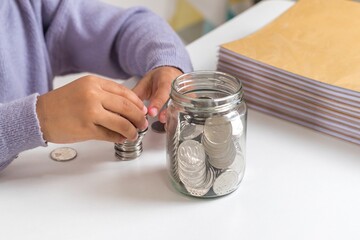 A little girl stacking and counting coins on the table. Savings money.