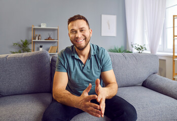 Portrait of a happy man sitting on the sofa at home, enjoying a chill moment of rest and...