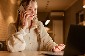 portrait of smiling young woman call to friend using cellphone in modern cozy cafe