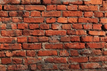 Fototapeta premium Textured red brick wall with visible mortar joints, showcasing wear and dirt, adds rustic charm and vintage appeal to any design or decor project