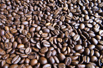 Roasted coffee beans Background. Aromatic coffee. Close-up of scattered dark brown coffee beans. Backdrop for coffee shop branding or menu design.