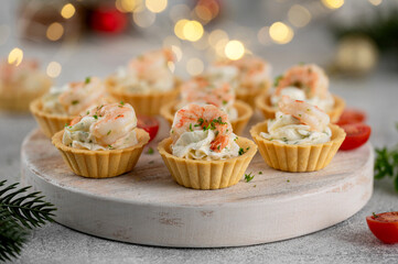 Christmas food. Tartlets with shrimp, cream cheese, garlic and parsley on a wooden board on gray concrete background.