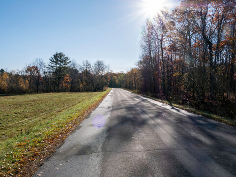 Country road in Maine with the sun low in the sky.