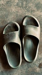 Old plastic sandals on rough cement floor with natural light and texture. A simple still-life photo representing minimalism, everyday comfort, and authentic lifestyle aesthetics.