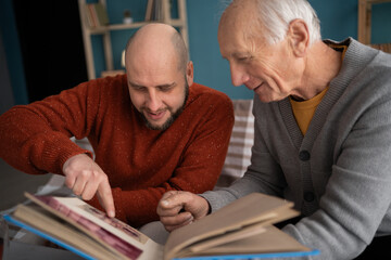 Happy fathers day concept. adult son with his old elderly senior father looking family photograph...