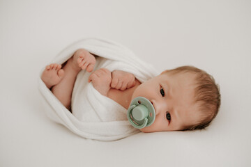 newborn, baby sucking a pacifier in a diaper with open eyes on a white bed, newborn baby sleeping...