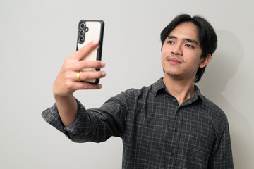Portrait of handsome Young Asian Thai man using phone against white background