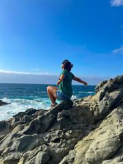 Joyful brunette woman with sunglasses and open arms on Fuerteventura beach