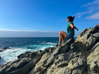 Joyful brunette woman with sunglasses and open arms on Fuerteventura beach