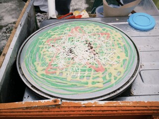 Process of making Kue Jala or Indonesian crepes with chocolate and cheese toppings