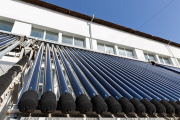 A close-up view of an evacuated tube solar water heater collector. This innovative system, angled towards the sun, represents clean energy, sustainability, and energy-saving technology.