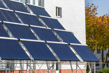 A large installation of evacuated tube solar water heaters mounted on a frame. These panels collect thermal energy from the sun to heat water for a swimming pool, promoting energy saving and autonomy.