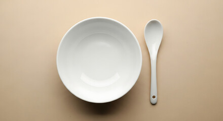 A simple still life featuring a white bowl and spoon on a neutral colored background in a minimalist style