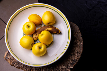 Gros plan sur un saladier contenant des pommes, une banane et un citron, mettant en valeur les textures et les couleurs naturelles des fruits frais.