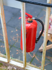 Red Fire Extinguisher Mounted on Outdoor Metal Fence