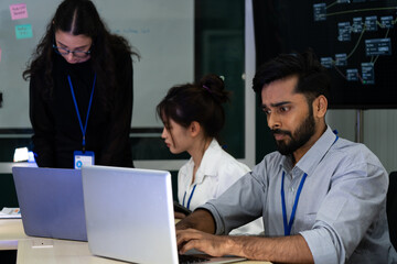 Business team analyzing data on laptops with growth chart in background. Diverse professionals collaborating in office, discussing financial performance, strategy, and success analytics in workplace.