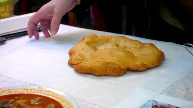 Hands adding salt to Krumplis Langos before serving at Szimpla Kert
