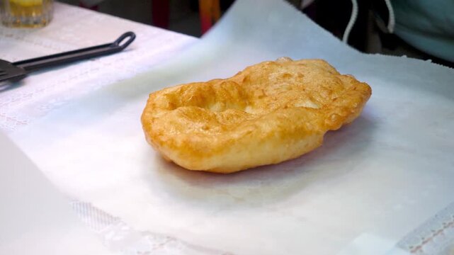 Hands preparing Krumplis Langos with sour cream and cheese