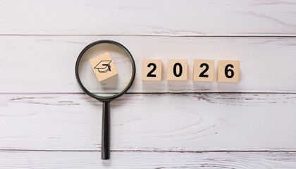 Black Graduation Cap Icon Under Magnifying Glass with Wooden 2026 Year Blocks