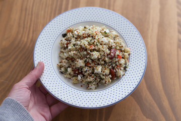 Hand holding plate with quinoa salad