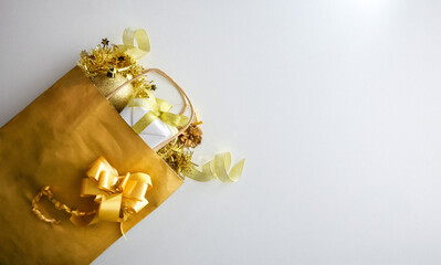 Golden shopping bag with gifts and deco on white table