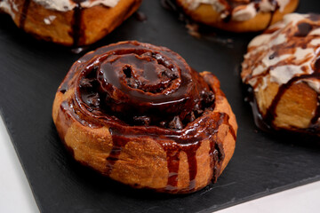 Chocolate roll drizzled with chocolate sauce on slate