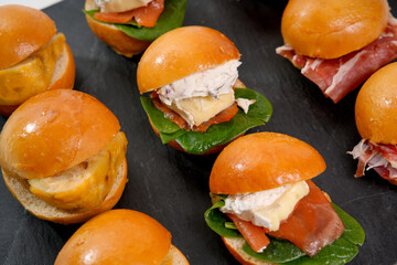 Assorted mini sliders arranged on dark slate catering tray