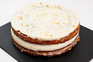 Homemade carrot cake with cream cheese frosting on slate