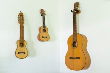 Fototapeta premium Wooden Instruments - Guitars, Ukelele, Charango - on a white wall