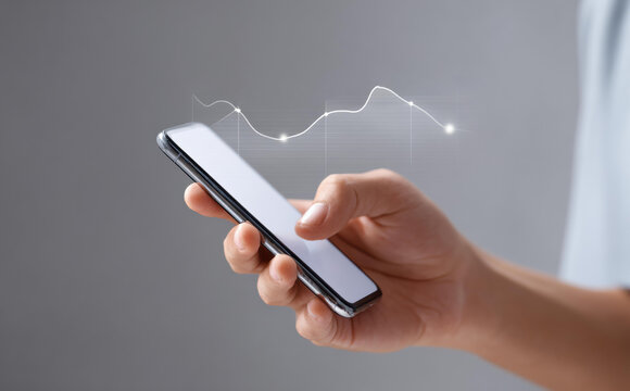 Focused hand holding phone with glowing graph showing business data. Technology for finance market analysis indicating successful growth and investment strategy online