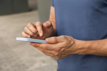 Man using and texting mobile phone. Check apps, focused on device, chatting or browsing internet. Online. Outdoors.