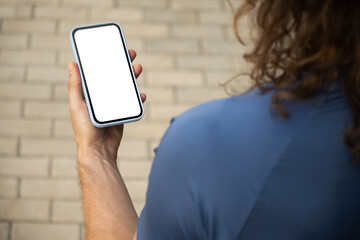 Athlete or sporty fit man holding mobile phone with empty white blank screen at modern city. Mock up. Check apps, focused on device, chatting or browsing internet. Outdoors.