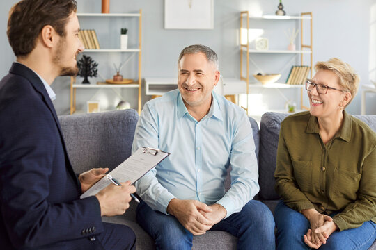 Fototapeta Friendly male financial advisor or realtor meeting with senior couple sitting on sofa. Happy smiling pensioners discussing investment options and life insurance decisions during consultation at home.