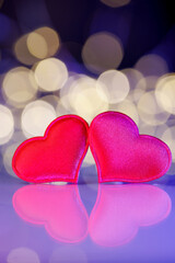 Fototapeta premium Two red hearts with golden bokeh lights. Romantic holiday background for Valentine’s Day, anniversary, wedding, or New Year greeting cards. Symbol of love, joy, and celebration.