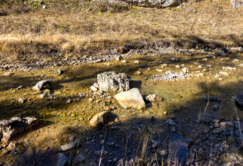 Autumn walks along the banks of a mountain river with clear, cool water in the morning hours with the rising sun