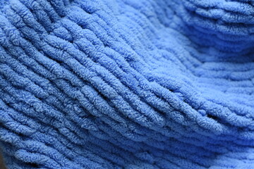 Soft knitted blanket close-up showing detailed texture and cozy fabric pattern. Warm home textile for comfort and interior design concepts.