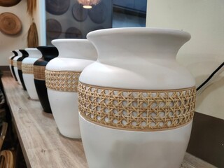Close-up perspective of decorative ceramic vases with woven rattan accents, arranged in a neat row...