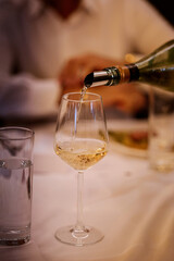 A waiter pours wine in a restaurant in the evening