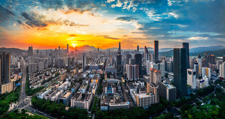 Fototapeta premium Panoramic of the dense urban city skyline with modern skyscrapers under a golden sunset sky in Shenzhen, China.