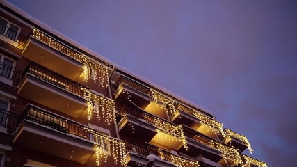 Elegant holiday lights illuminate apartment balconies against dusk sky