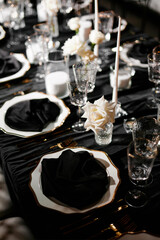 Luxurious setting of dark restaurant tables with candles and fresh flowers
