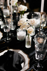 Luxurious setting of dark restaurant tables with candles and fresh flowers