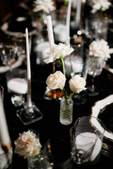Luxurious setting of dark restaurant tables with candles and fresh flowers