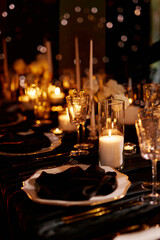 Luxurious setting of dark restaurant tables with candles and fresh flowers
