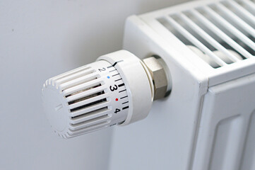 Close up of thermostatic radiator valve with numbered control settings and metal connections.