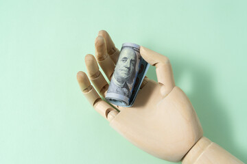 Wooden hand model holding dollar banknote